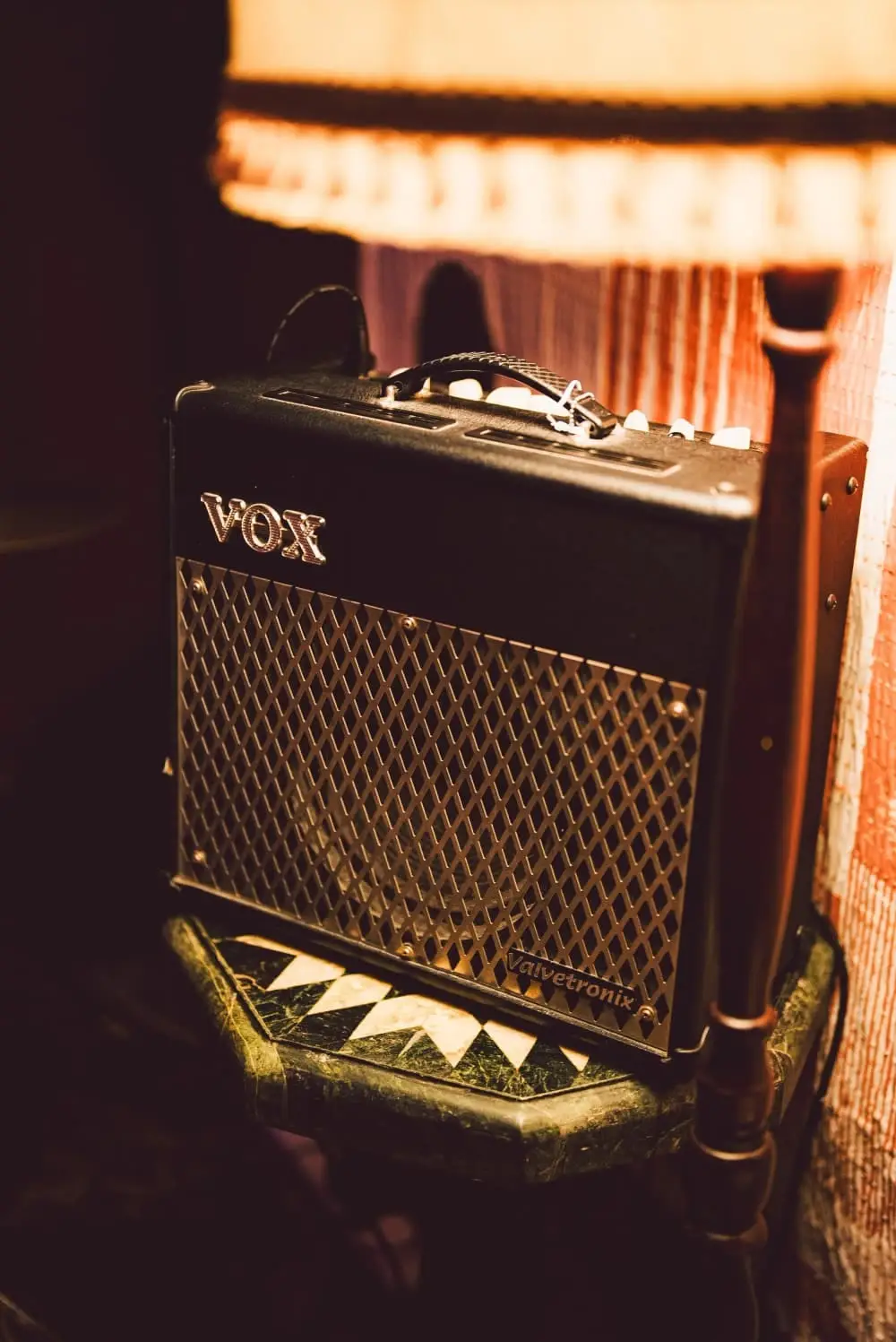 A Vox amp on the basement floor under a lamp