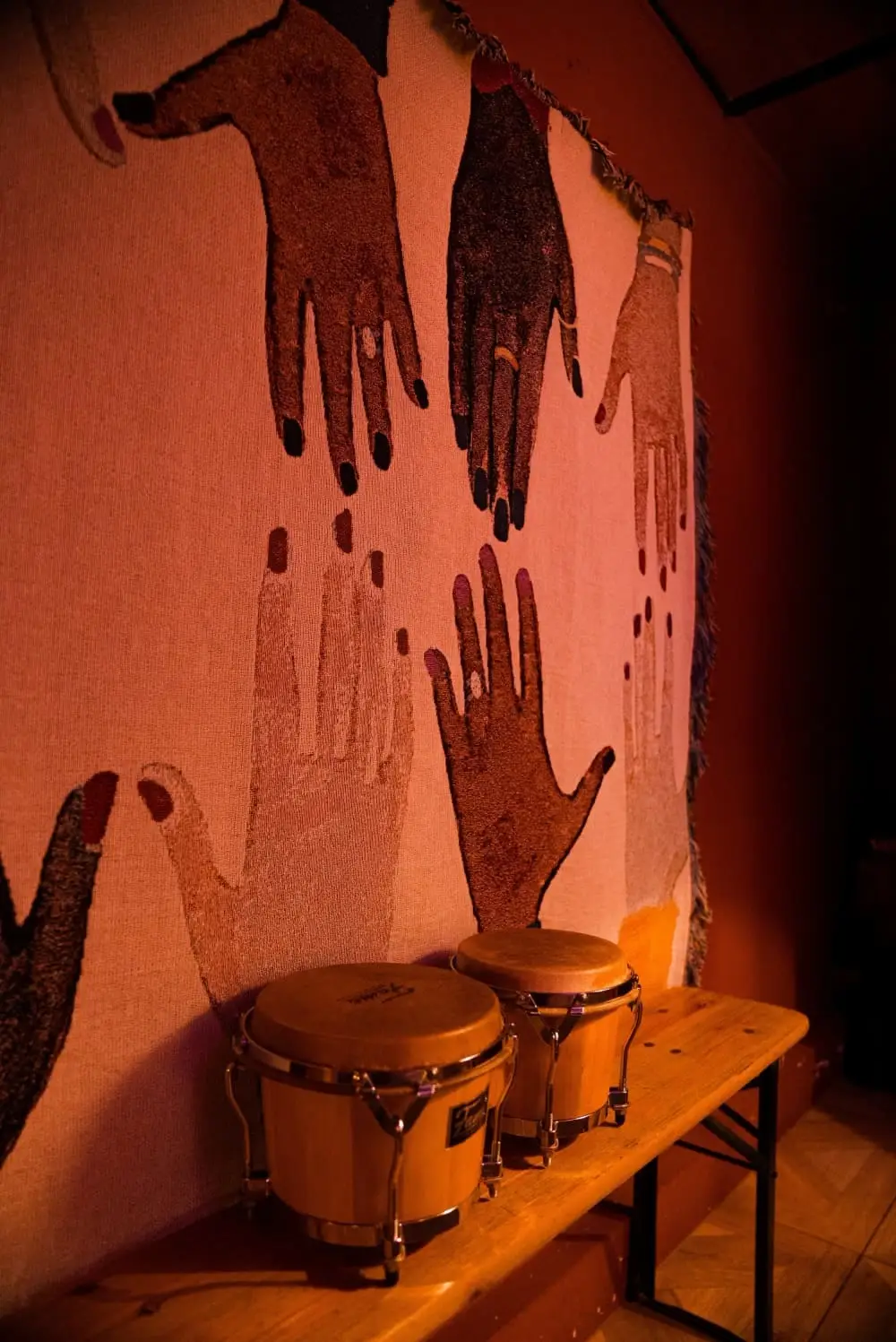 Bongos on a bench under a mural of hands
