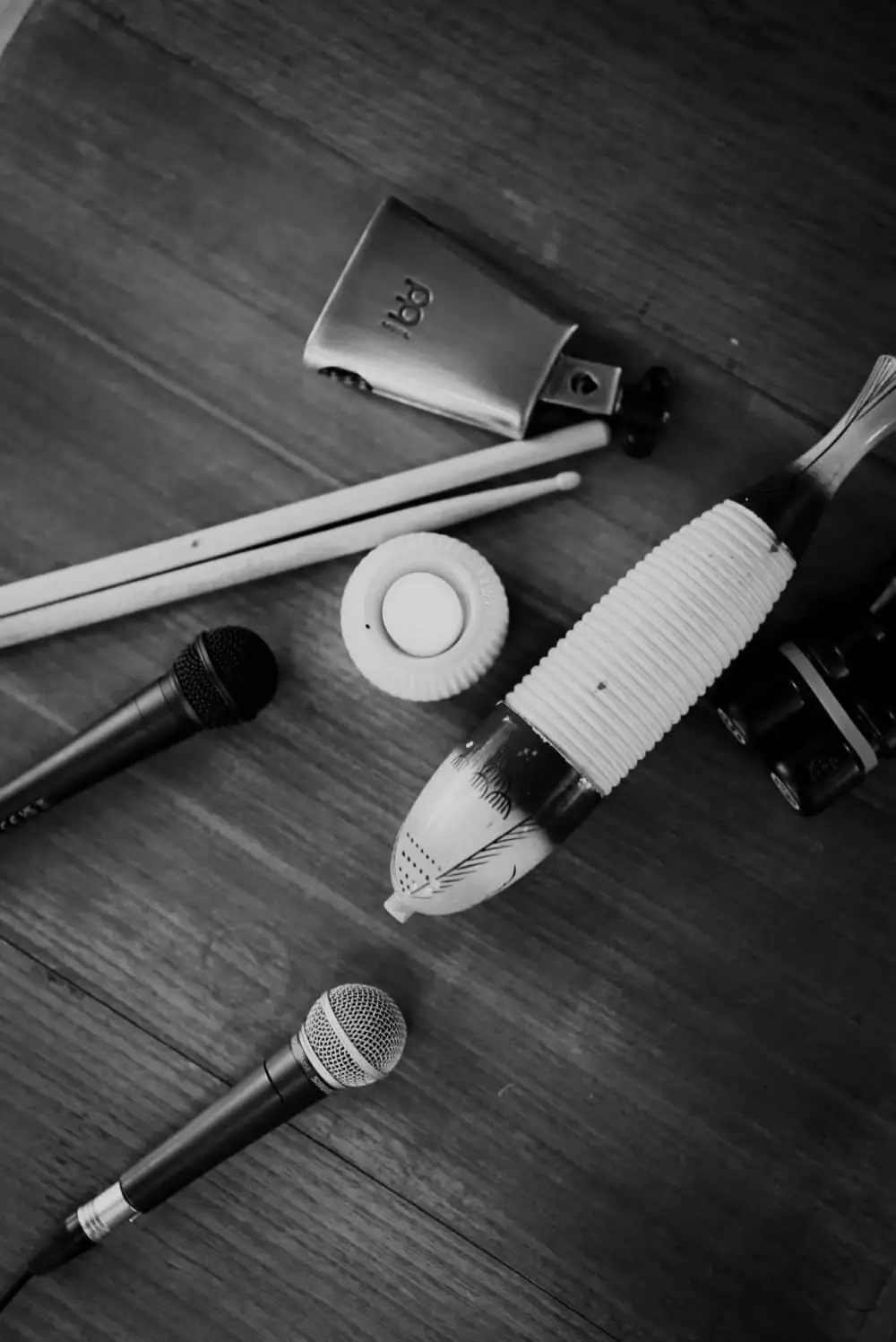 Microphones, drumsticks and shakers on the basement floor, in black and white