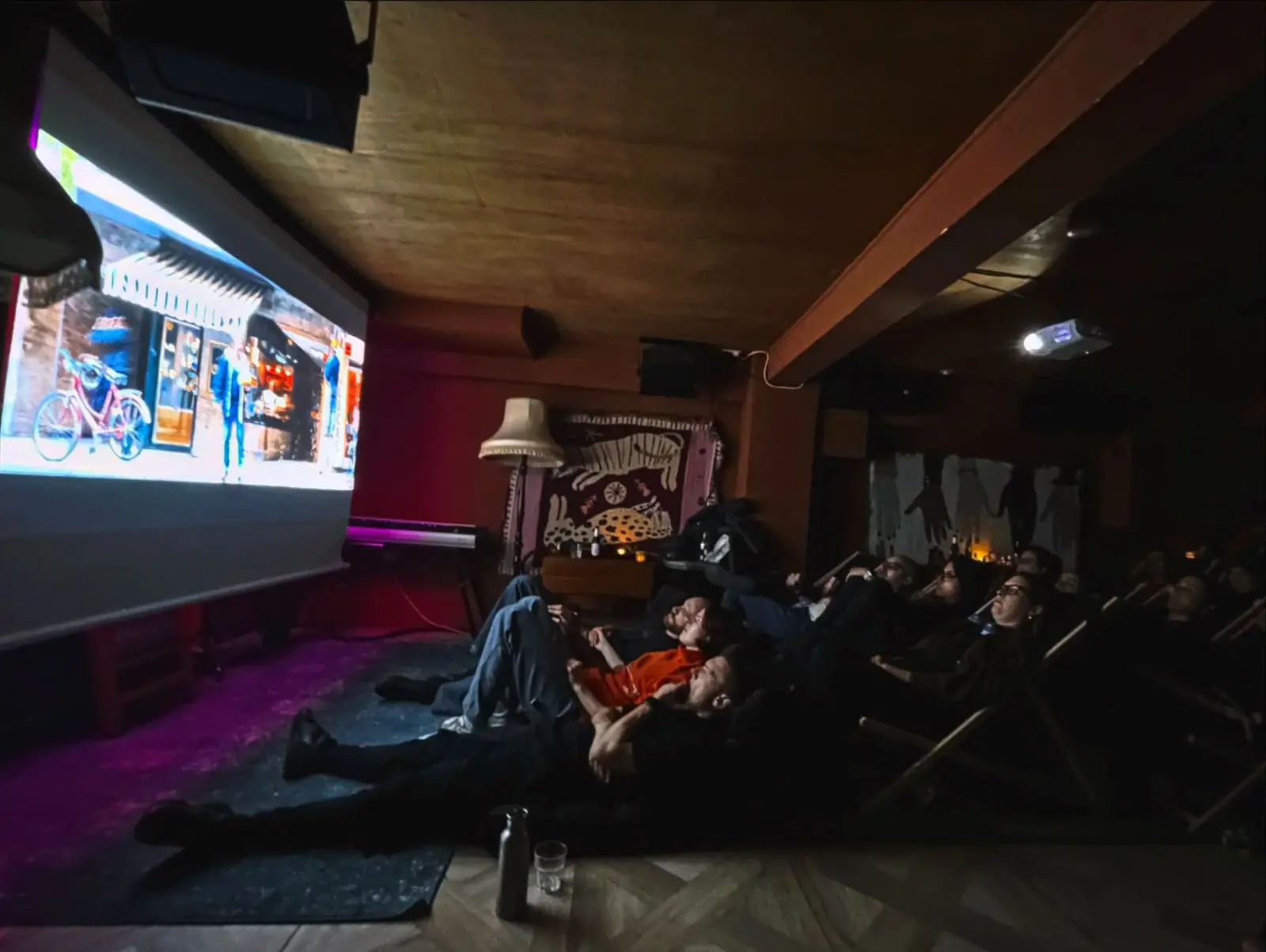 A film screening in the basement, the audience on low seats facing the projector